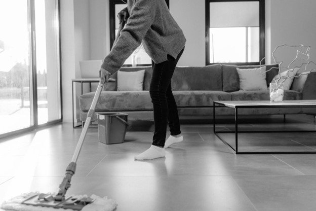 A woman cleaning the floor inside a living room