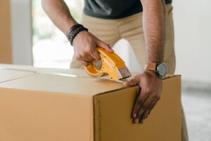 Man tapping a cardboard box with scotch