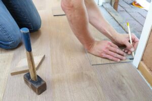 Person measuring planks on the floor with a pencil